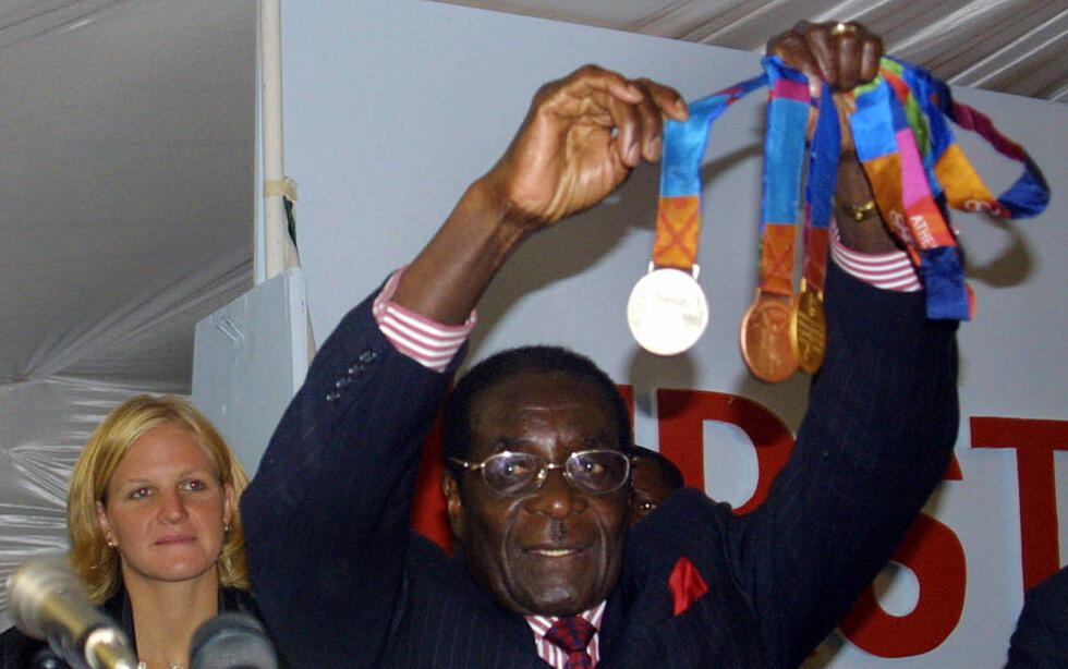 Zimbabwe's then president Robert Mugabe shows off Kirsty Coventry's Olympic medals after the 2004 Athens Games